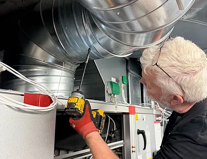 Ventilationsaggregat med isolerade luftkanaler och kontrollpanel i teknikrum.
